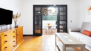 A living room with a TV, wooden cabinet, and a table. - Home2Book Sunny Apt Pool & Terrace, Las Américas (Playa de la Américas)
