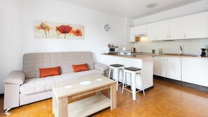 A modern living room with a sofa, a coffee table, and a kitchen area with white cabinets and a microwave. - Home2Book Sunny Apt Pool & Terrace, Las Américas (Playa de la Américas)