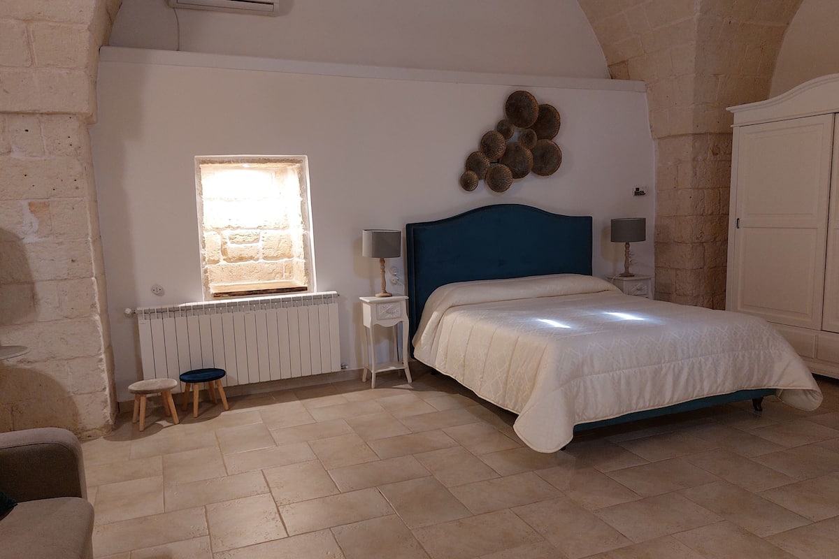 Ein Schlafzimmer mit Bett, Fenster, Heizkörper, Lampe und Kleiderschrank.