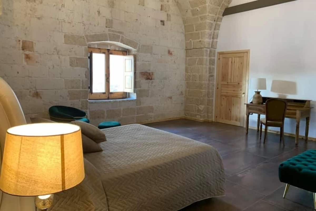 Ein Schlafzimmer mit Bett, Schreibtisch, Stuhl und Fenster.