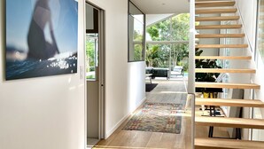 Een modern interieur met een houten trap, een groot raam en uitzicht op groen.