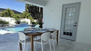 Eine Terrasse im Freien mit Esstisch, Stühlen und einem Pool.