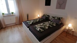 A modern bedroom with a large bed, bedside lamps, and a window with curtains.