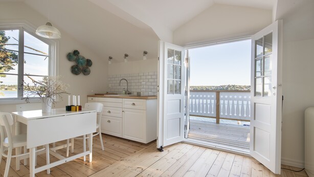 A bright kitchen with white cabinetry, a wooden floor, and a large window. - Beautiful Lofthouse, a cottage on a private beach lot by Lake Mälaren (Ekerö)