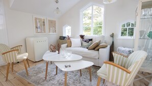 A cozy living room with a white sofa, striped armchairs, a white coffee table, and a vintage radio. - Beautiful Lofthouse, a cottage on a private beach lot by Lake Mälaren (Ekerö)