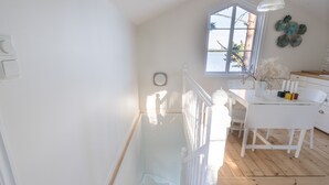 A bright room with a wooden floor, a white staircase, and a window overlooking a body of water. - Beautiful Lofthouse, a cottage on a private beach lot by Lake Mälaren (Ekerö)