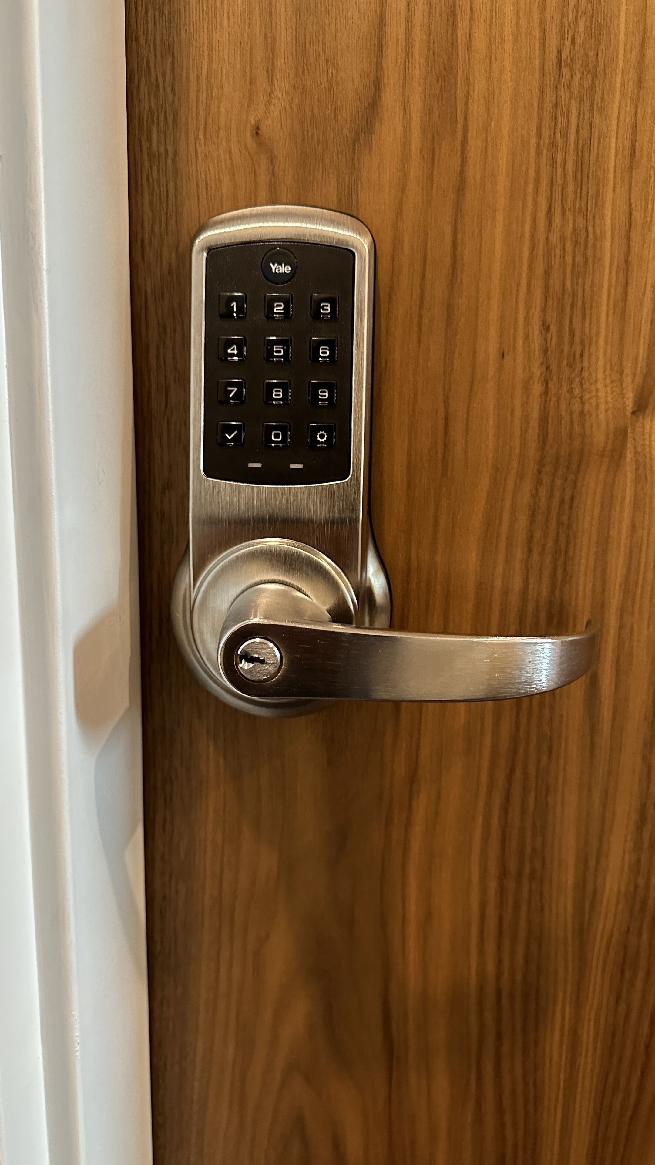 A Yale door lock with a numeric keypad on a wooden door.