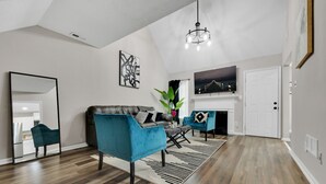 Una sala de estar moderna con chimenea, un espejo grande y una araña.