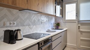 A modern kitchen with a herringbone tile backsplash, stainless steel appliances, and wooden cabinets. - Ilisia Park Contemporary 2BD Condo (Athens)