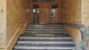 A staircase leading to a wooden door with a brass handle, flanked by wooden handrails and a small mat at the bottom. - Ilisia Park Contemporary 2BD Condo (Athens)
