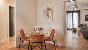 A modern dining area with a glass table and velvet chairs, a decorative vase, and a painting on the wall. - Ilisia Park Contemporary 2BD Condo (Athens)