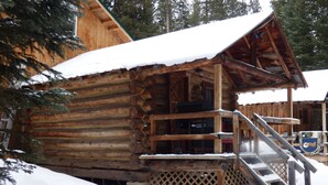 Une cabane en rondins avec une façade en bois, une véranda et un escalier menant à l’entrée.