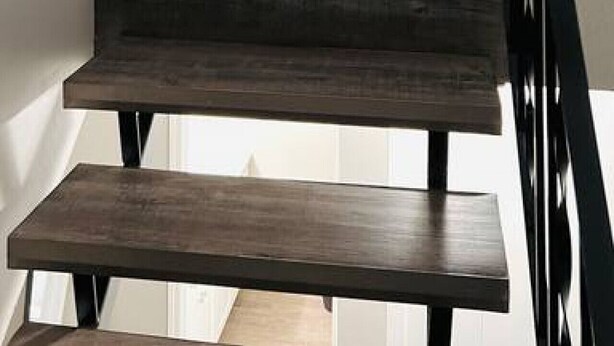 Eine Treppe führt zu einer Küche mit weißen Schränken und einem gerahmten Bild an der Wand.