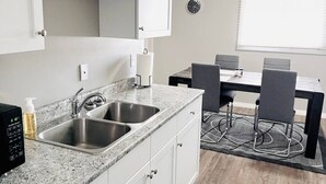 Eine moderne Küche mit zwei Edelstahl-Spülen, einem eingebauten Backofen und einer Essecke mit Tisch und Stühlen.