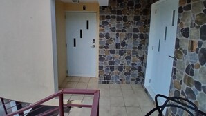 Un pasillo con suelo de baldosas, una puerta marcada con el número 7 y una pared de piedra con una puerta marcada con el número 6.