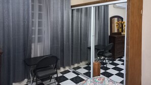 Una habitación con piso a cuadros, un escritorio, una silla, un armario y un espejo.