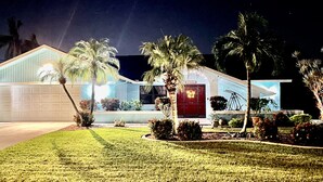 A modern house with a garage, palm trees, and well-maintained lawn.