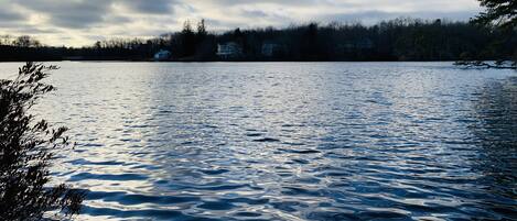 A calm lake with reflections of the sky and surrounding trees.
