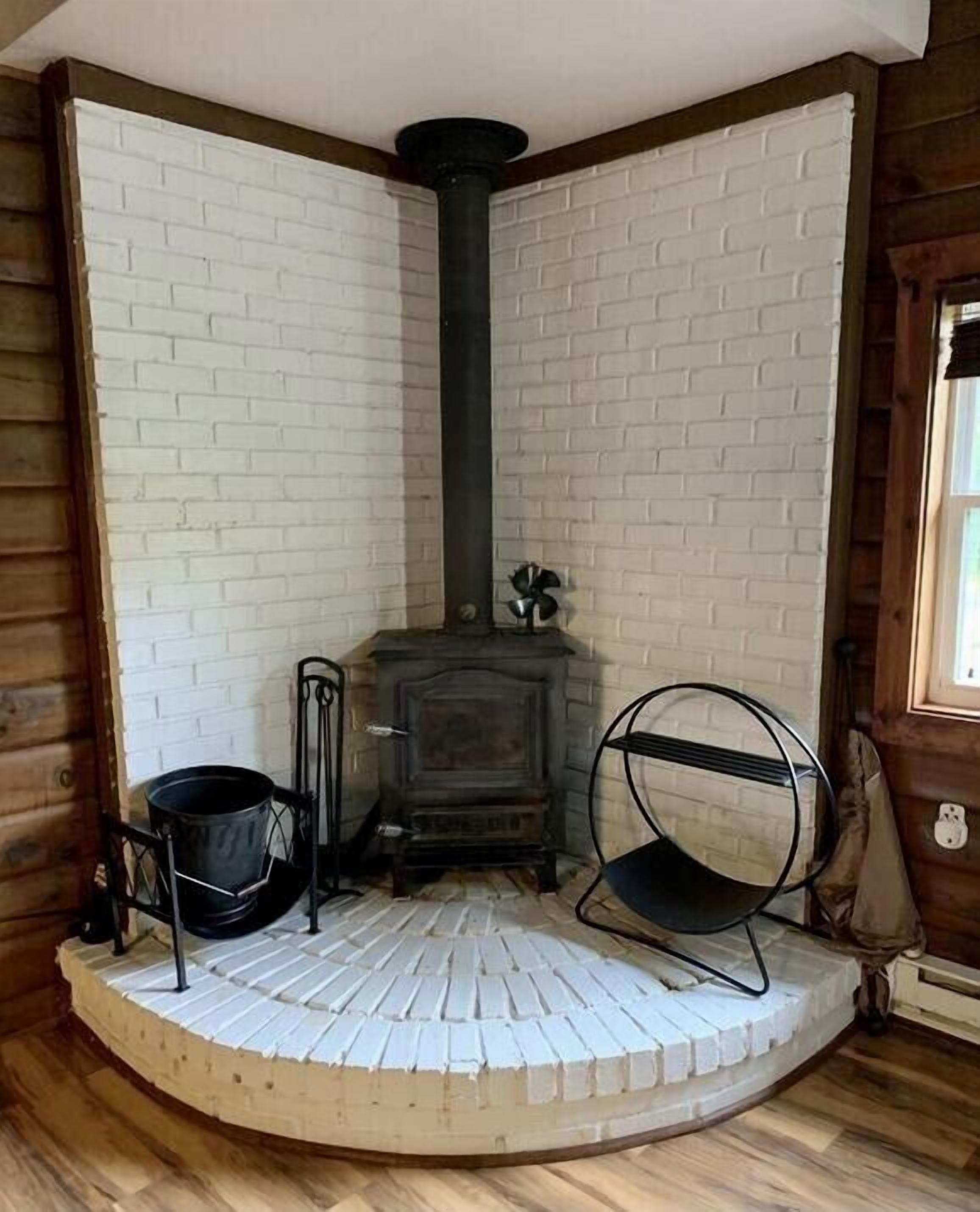 Una habitación de esquina con chimenea, un banco de madera y una silla de metal.