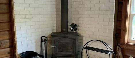 Una habitación de esquina con chimenea, un banco de madera y una silla de metal.
