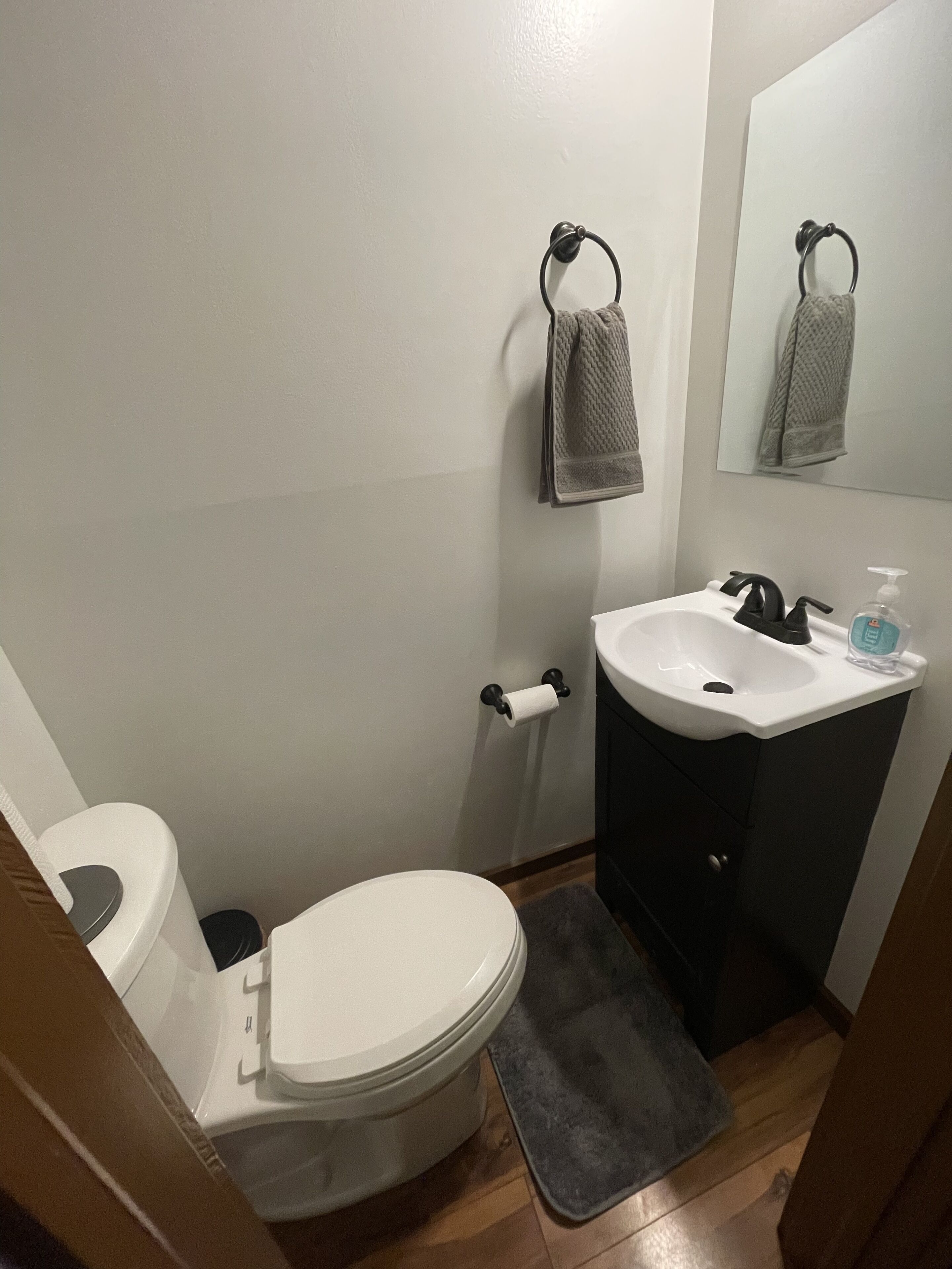 A bathroom with a toilet, sink, and mirror.