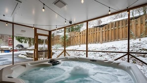 Un jacuzzi con cerramiento de madera y nieve afuera.