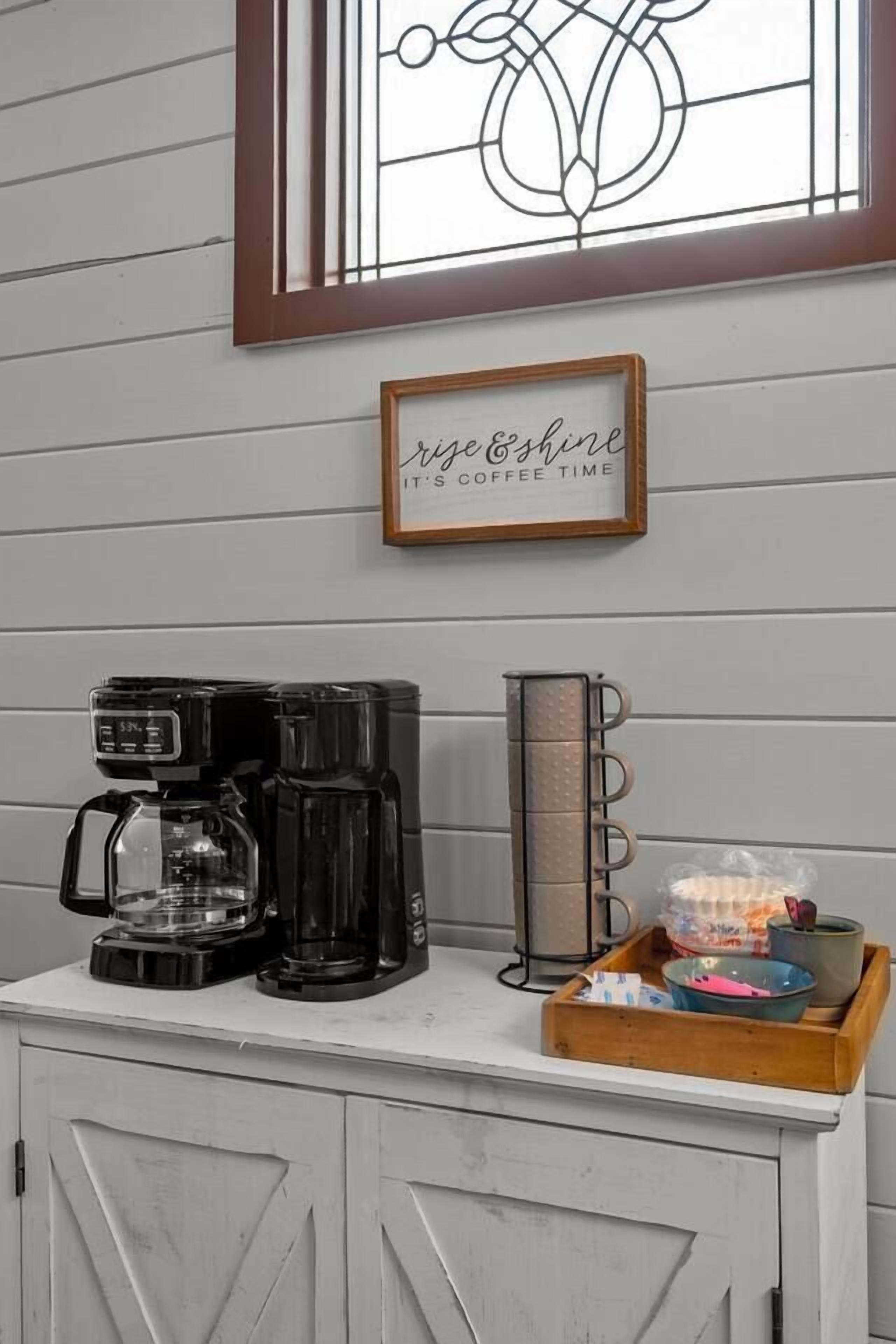 Eine Kaffeestation mit einer Kaffeemaschine, einer Tablett mit Kaffeetassen und einem Schild mit der Aufschrift 'Kaffezeit'.