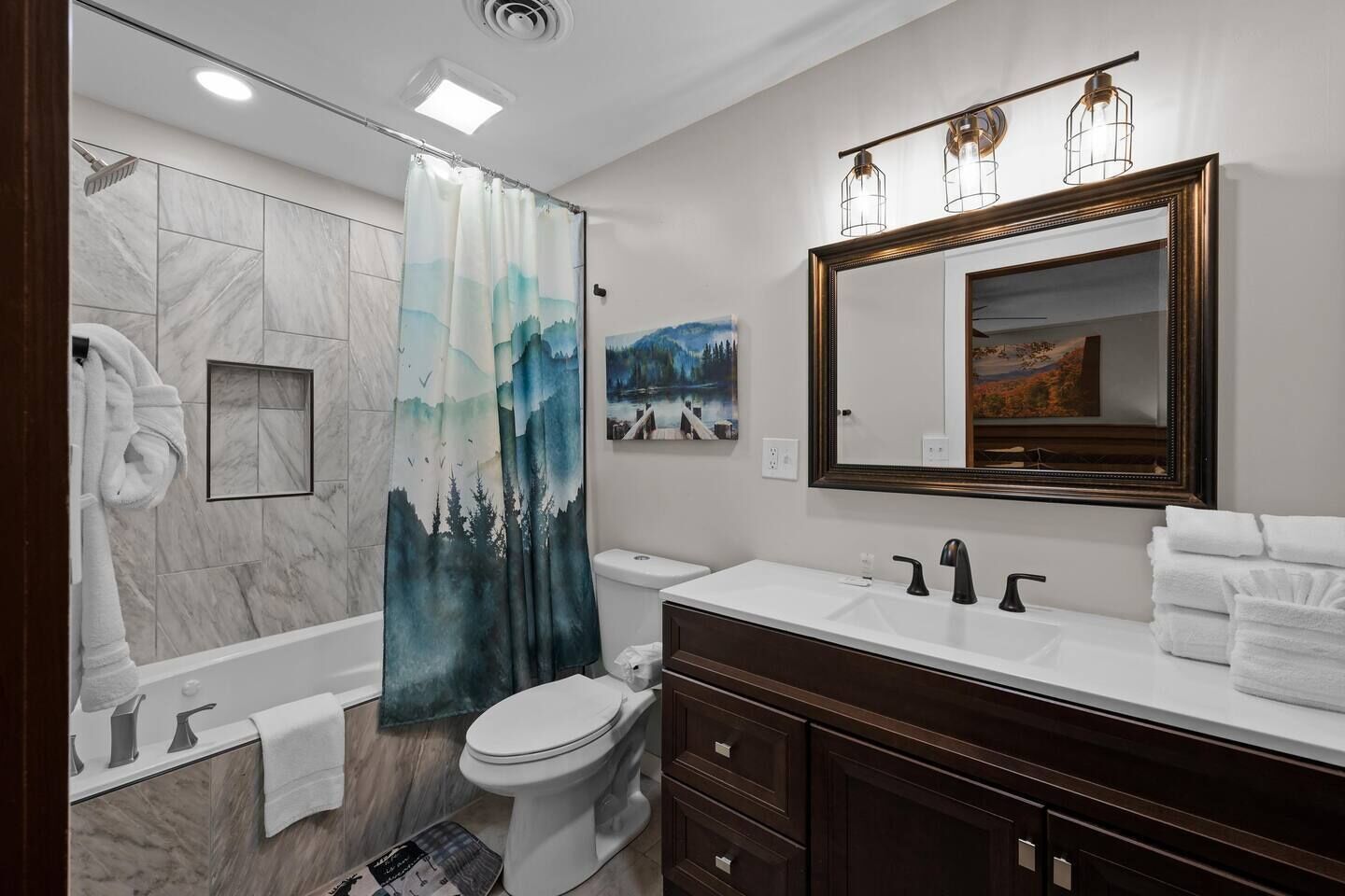 A modern bathroom with a bathtub, toilet, and vanity.