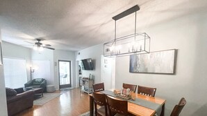 Un coin repas avec une table et des chaises en bois, un ventilateur de plafond et un lustre moderne.