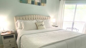 Une chambre à coucher avec un grand lit, une table de chevet et une fenêtre avec des stores.