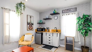 Un espacio habitable compacto con kitchenette, comedor y zona de estar.