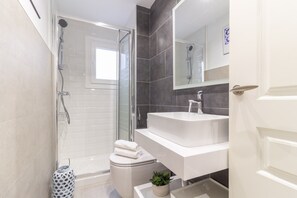 Ein modernes Badezimmer mit einer gläsernen Duschkabine, einem weißen Waschbecken und einer Toilette.
