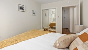 Une chambre à coucher comprenant un lit, un ventilateur de plafond, une lampe de chevet et une porte donnant sur une autre pièce.