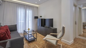 Un salon moderne avec un canapé, un téléviseur, un fauteuil et une petite table.