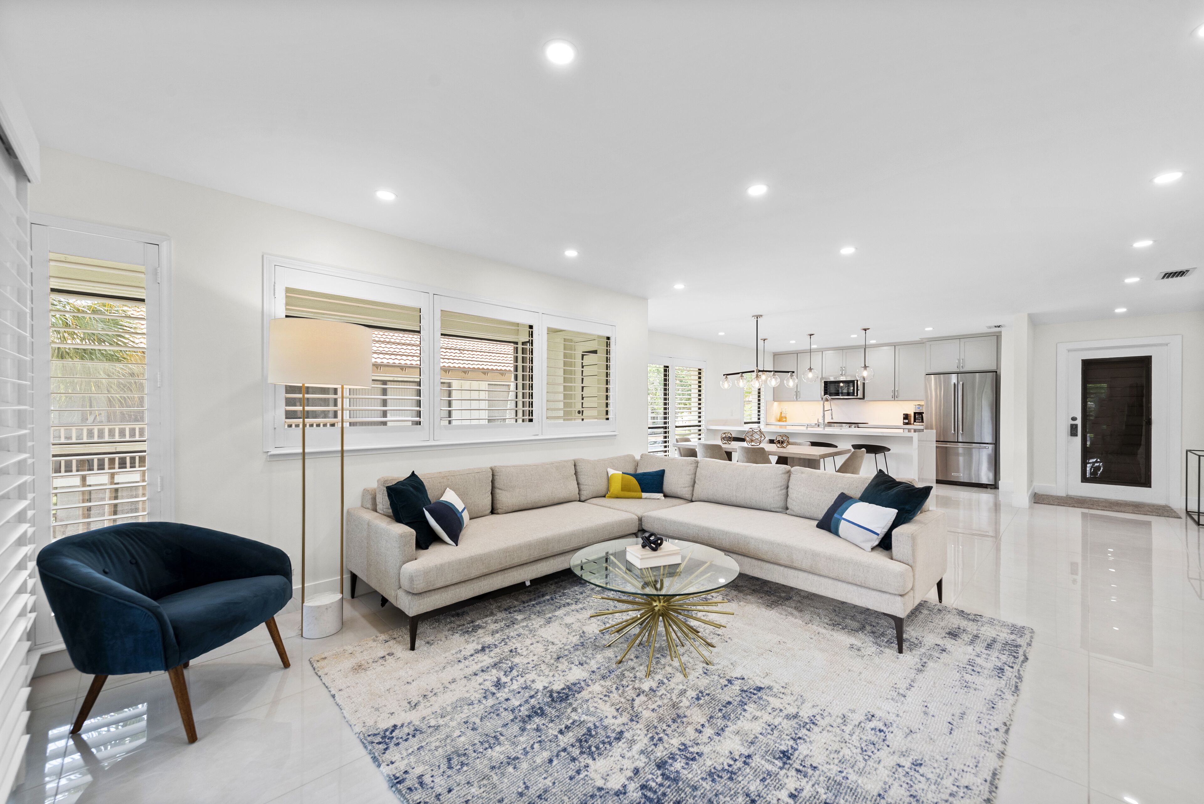 Una sala de estar moderna con un sofá modular, una mesa de centro de vidrio y un tapete azul estampado.