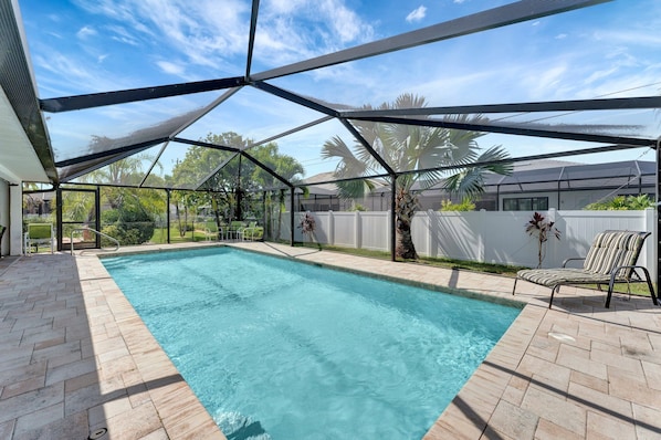 Una piscina techada con vistas claras del entorno, incluyendo un patio con una silla y una cerca blanca.