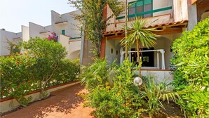 Un pati amb un camí empedrat, envoltat de vegetació exuberant i plantes amb flors.