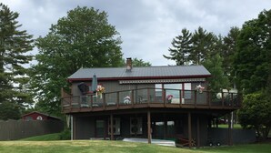 A two-story building with a balcony, a covered porch, and a fenced yard.