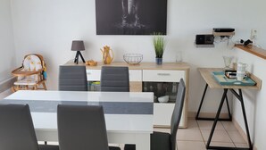 A modern dining area with a large table, black chairs, a wall-mounted clock, and a framed elephant artwork.