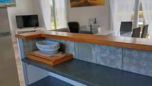 A modern kitchen with a built-in island, a flat-screen TV, and a dining area with chairs.