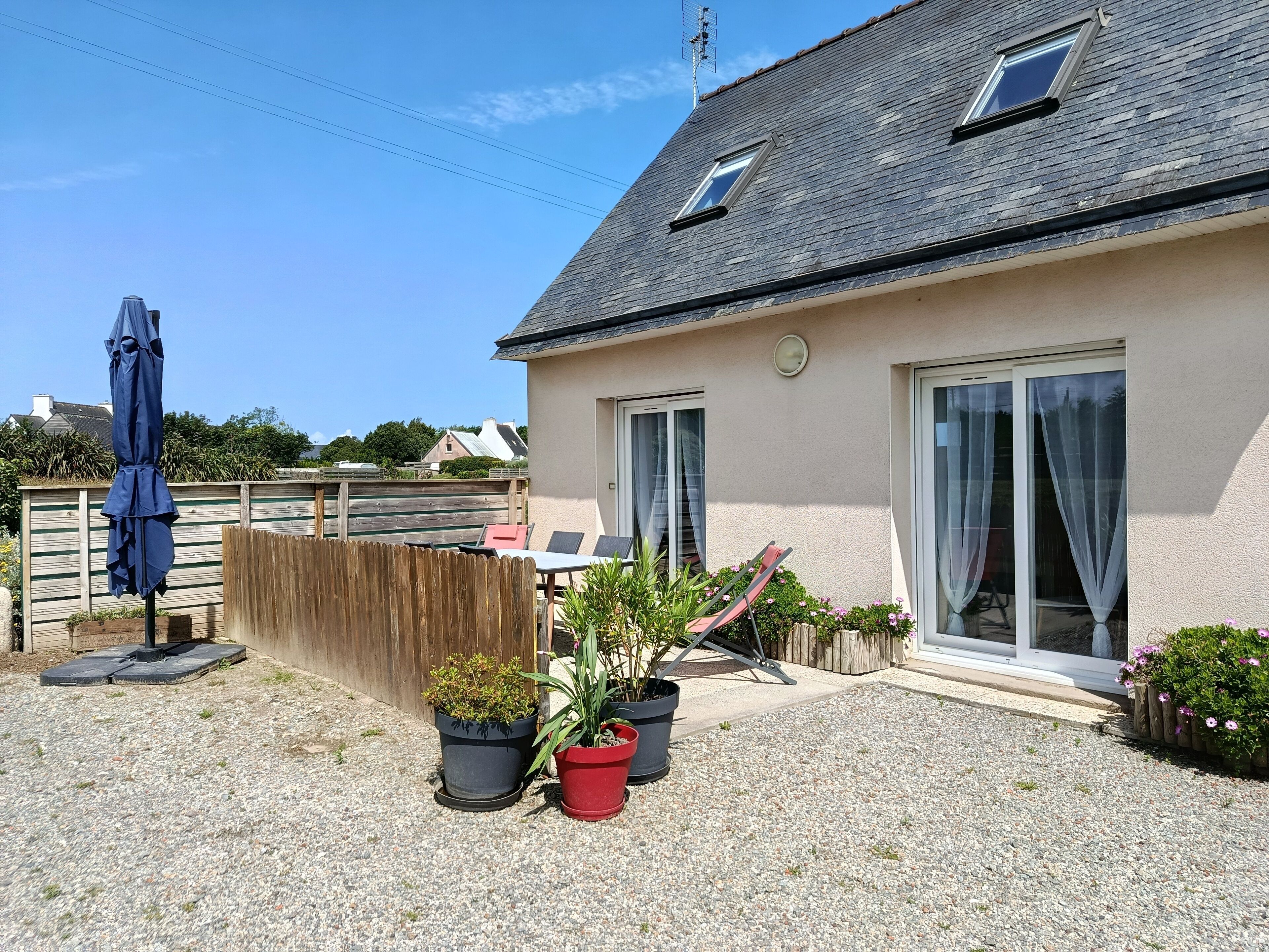 Une maison avec un toit en pente, une clôture en bois et une terrasse en gravier.
