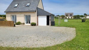 A two-story house with a sloped roof, a gravel driveway, and a fenced yard.