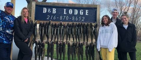 Eine Gruppe von Menschen steht vor einem Holunderschild mit dem Text "D&B LODGE 216-870-8652".
