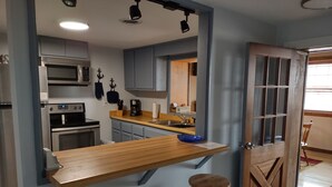 Een moderne keuken met een houten bar, roestvrijstalen apparatuur en een houten deur met glaspanelen.