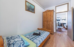 A bedroom with a bed, a wooden wardrobe, a painting on the wall, and a view into the kitchen. - 3 bedroom beautiful apartment in Pula (Pula)