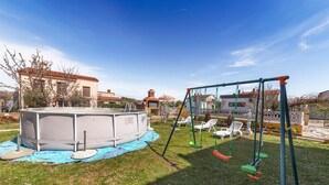 An outdoor swimming pool with a swing set and lounge chairs in a residential area.