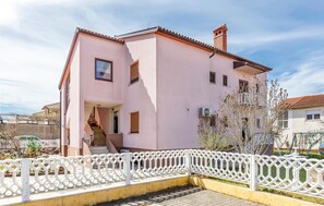 A pink building with a staircase, a white fence, and a tree in the yard. - 3 bedroom beautiful apartment in Pula (Pula)