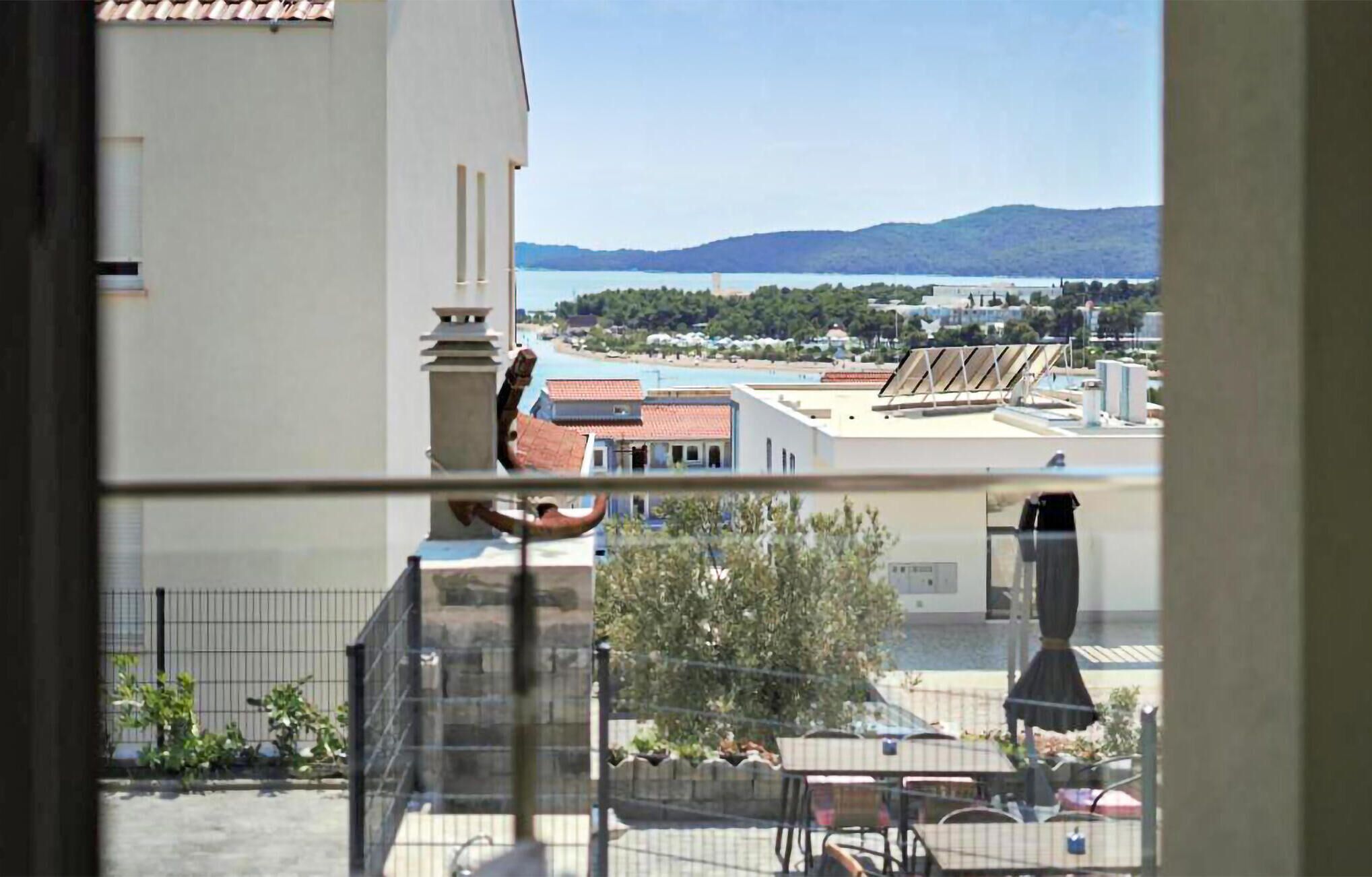 A balcony with a view of a cityscape, including buildings and a distant mountain range.
