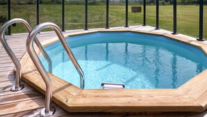A wooden deck with a swimming pool, metal ladder, and a grassy field in the background. - Cozy home in Sollebrunn with sauna (Sollebrunn)