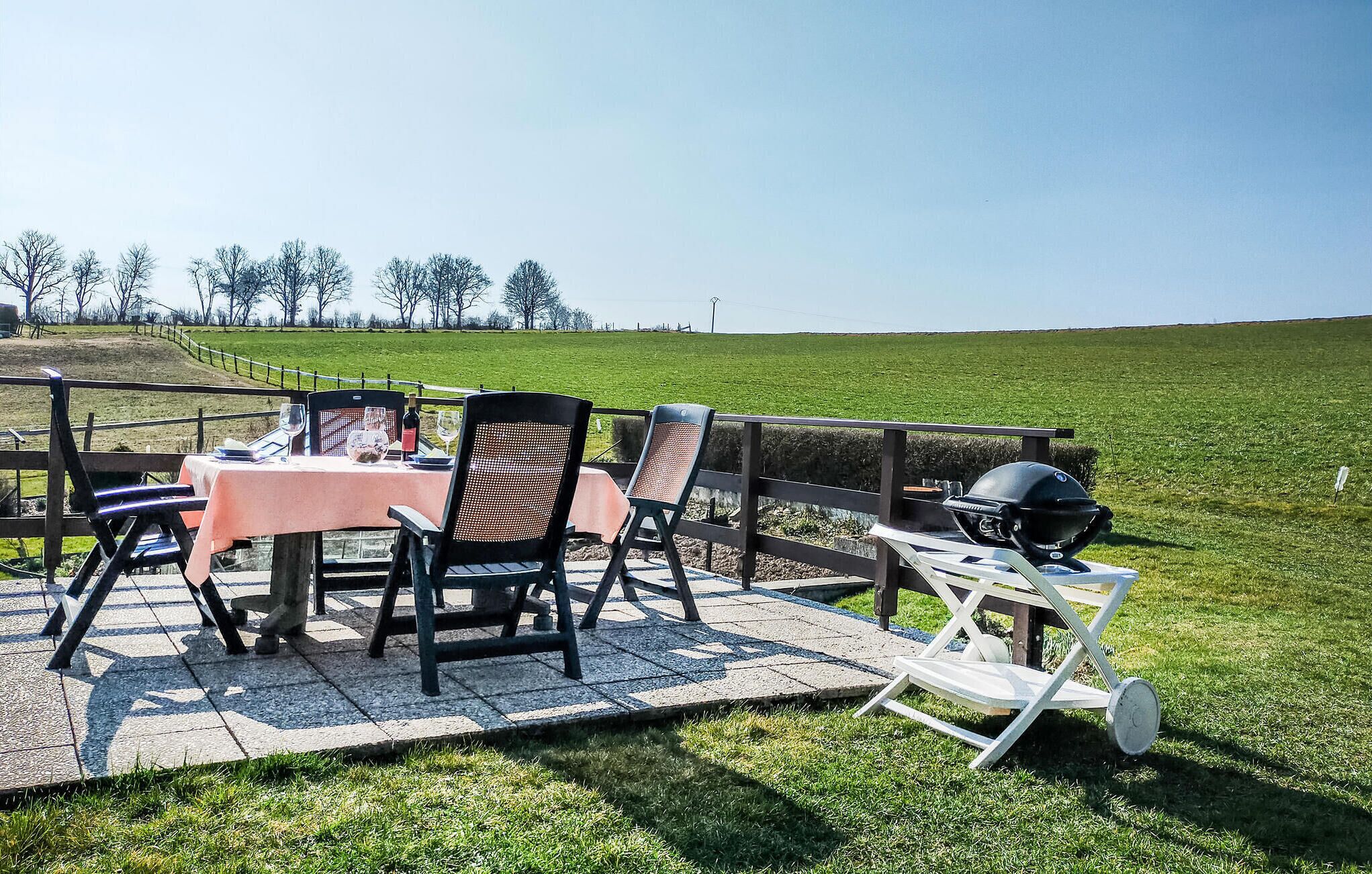 Un espace extérieur aménagé pour les repas, avec une table pour deux personnes, des chaises et un barbecue.